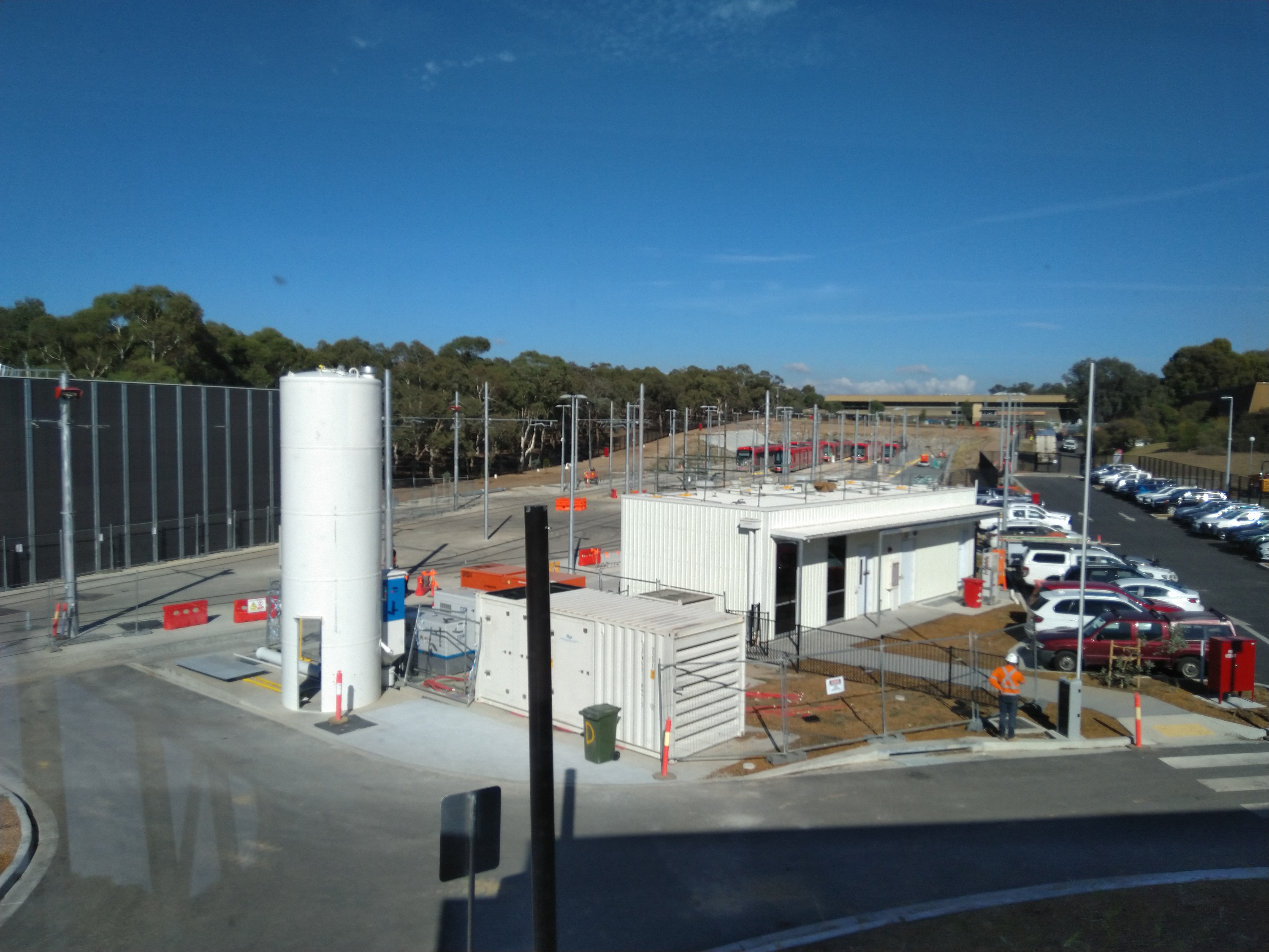 That large cylinder is a sand tower. Sand is used in the braking system to enhance friction between steel wheels and steel tracks, in an emergency. The building next to the carpark is the backup control centre. In the background the railyard, that houses the 14 light rail vehicles in our current fleet.